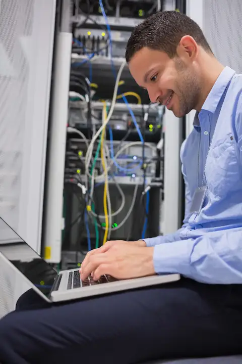 A UKNode engineer patching cables in front of an open server rack.