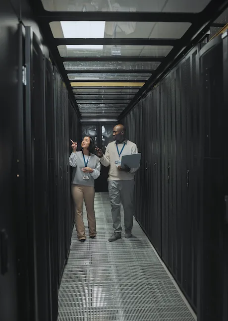 A UKNode engineer working at a laptop in front of an open server rack — smiling while patch-cabling.